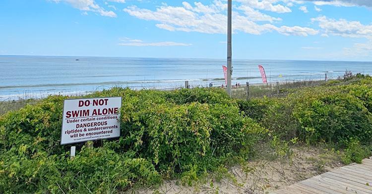 A warning sign on a beach that reads ''DO NOT SWIM ALONE''