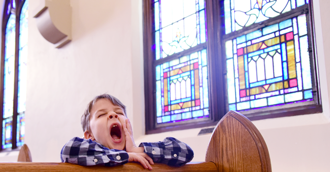 Kid sitting in a church pew and yawning