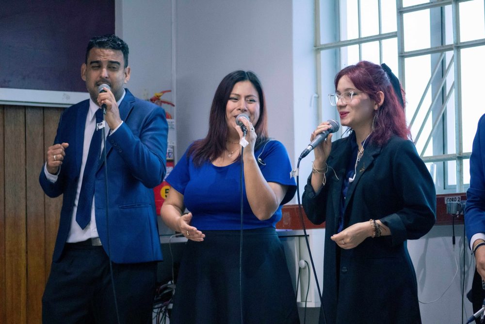 Two people climb up a snow-covered mountain Picture of three people holding microphones and singing