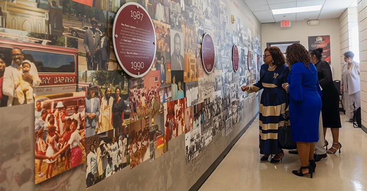 Several individuals looking at a historical timeline of the church