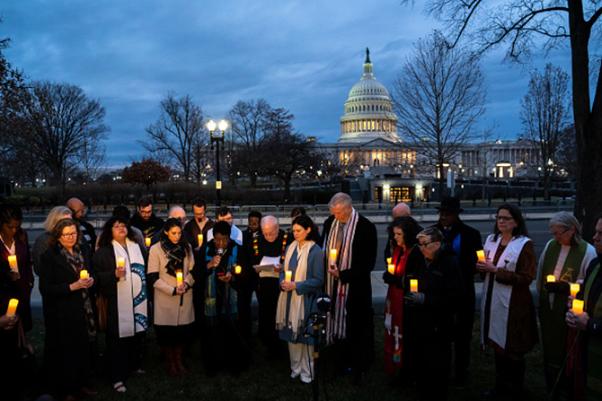 Community faith leaders gather in front of the Capitol building, holding candles for a prayer vigil on the second anniversary of the Jan. 6 attack on the Capitol in Washington, D.C.