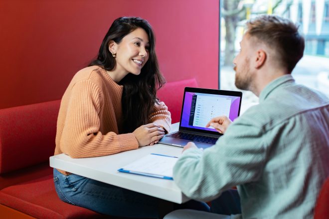 Man and a woman talking together with a computer in between them