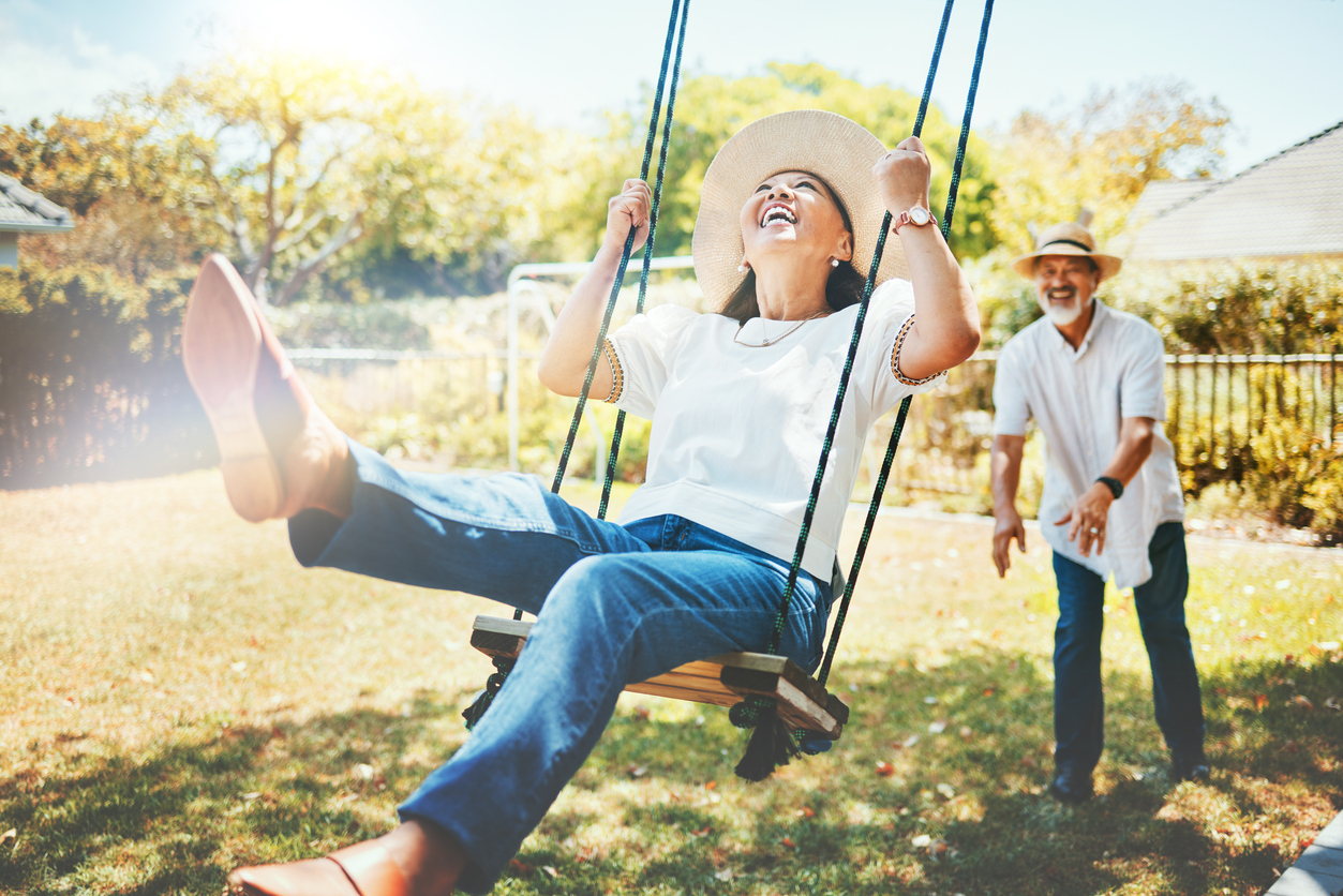 Woman being pushed on a swing while the sun is shining